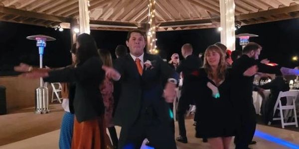 People dancing energetically under a decorated pavilion at night.