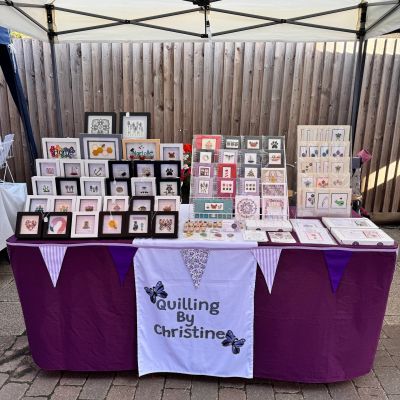 Quilling art display booth with framed pieces and cards at outdoor market.