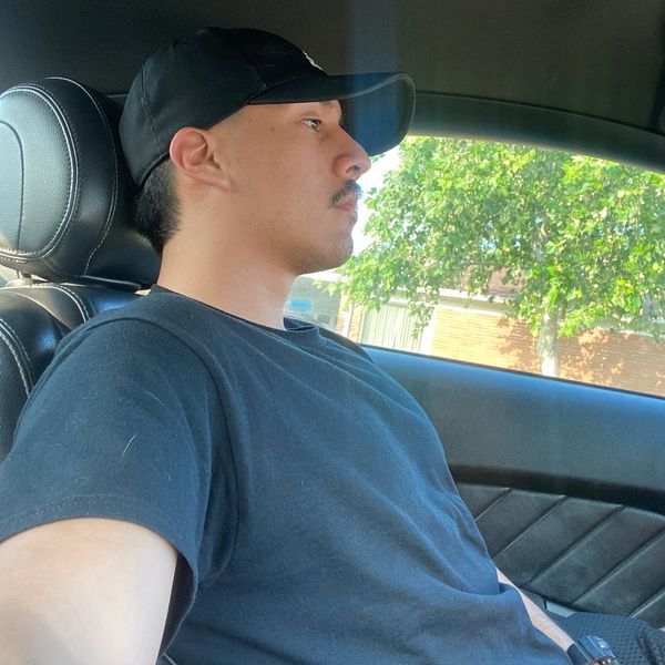 Young man wearing a black cap sitting in a car.