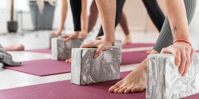 People practicing yoga using marble-patterned blocks on mats in a bright studio.