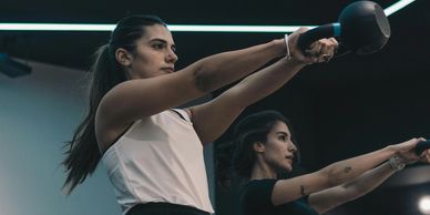 Two women exercising with kettlebells in a gym.