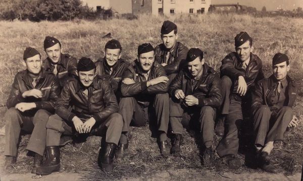 Five soldiers sitting on grass.
