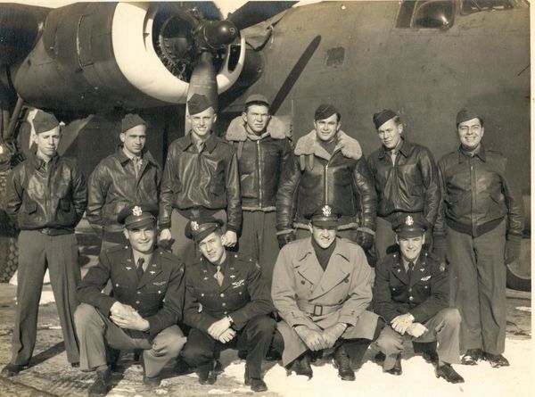Military crew posing before aircraft.