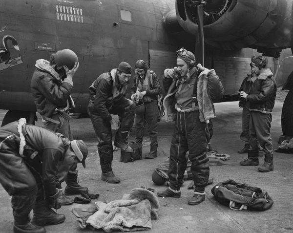 Airmen preparing gear by plane.
