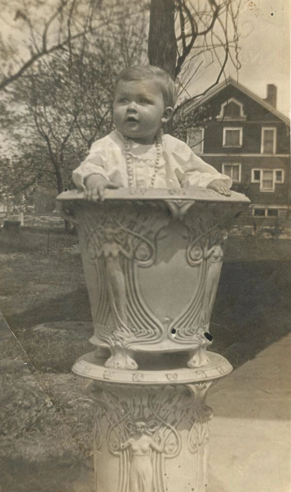  Baby standing inside large planter.
