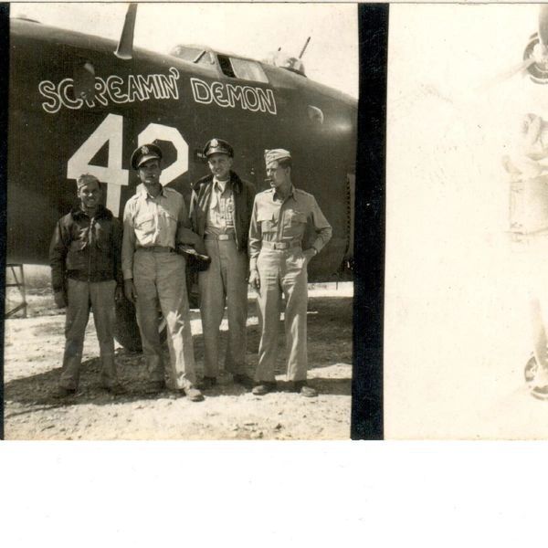 Crew standing by bomber nose.