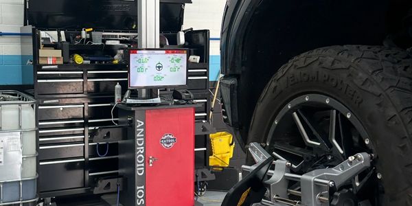 A car undergoing wheel alignment at an auto repair shop.