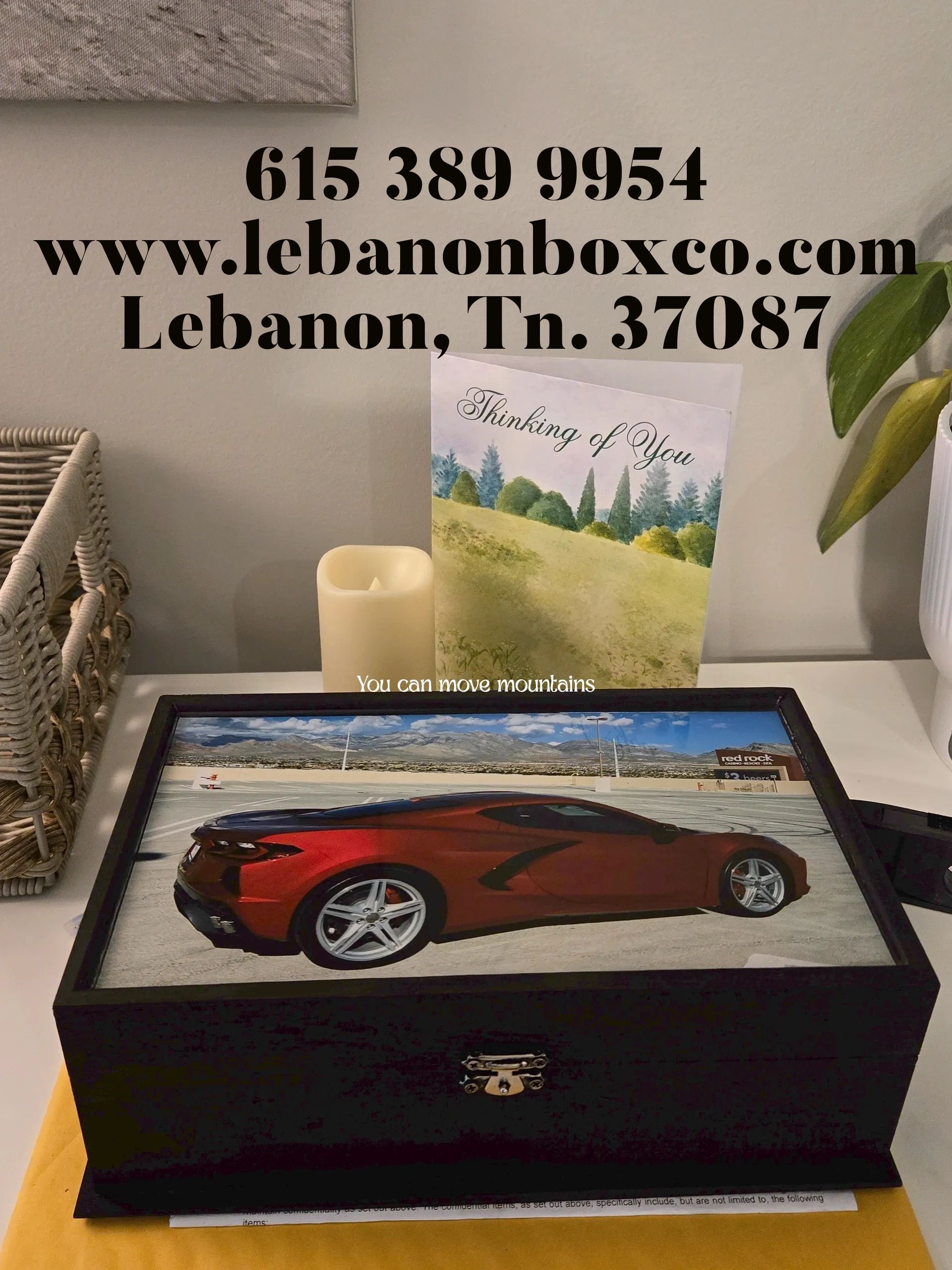 Decorative box with red car image and contact details on wall.