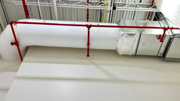 Red pipes and white ductwork along a ceiling.