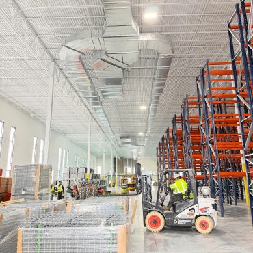 Indoor warehouse with workers and forklift.