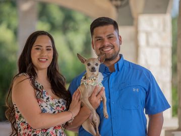 A pet photographer takes a picture of a small dog and its happy parents in Cedar Park Texas