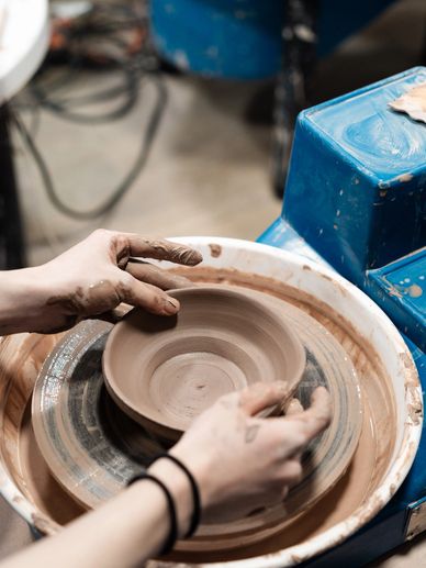 Hands shaping clay on a pottery wheel.