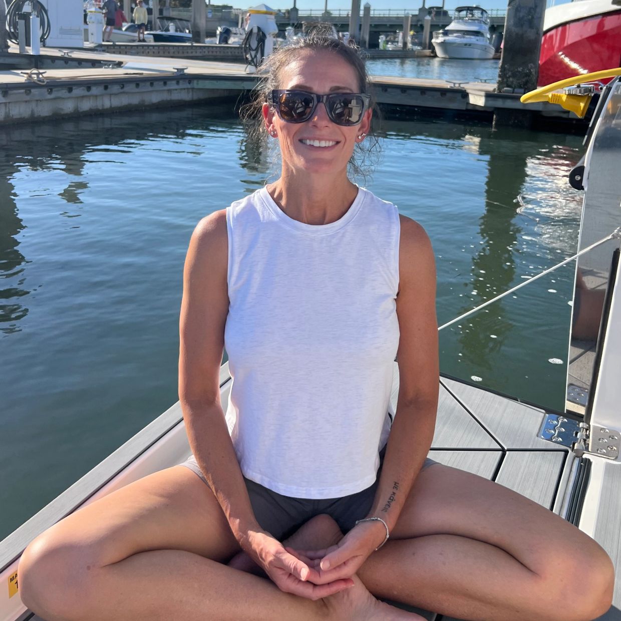 Woman practicing yoga at a marina on a sunny day.