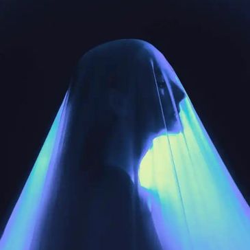 Silhouetted figure draped in glowing blue veil against dark background.