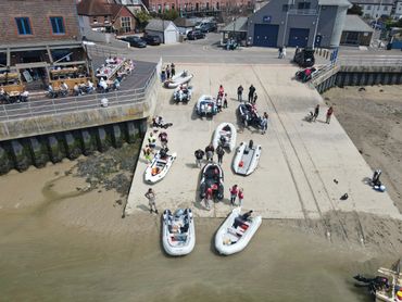 People gathered on a dock with small boats near the water.