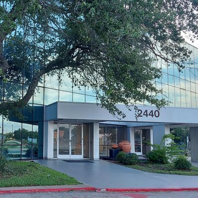 Office building entrance with address number 2440 and surrounding greenery.