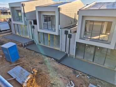 Newly poured concrete walkways outside modern townhouses under construction.