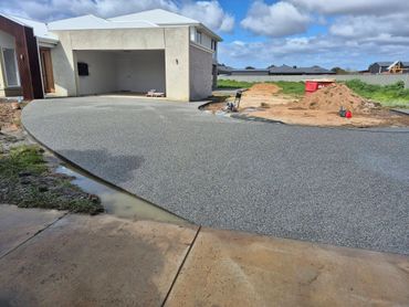 Newly paved driveway at a modern house under cloudy sky.