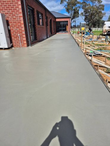 Freshly poured concrete walkway next to a brick building under sunny skies.