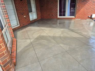 Empty tiled patio area with brick walls and windows.