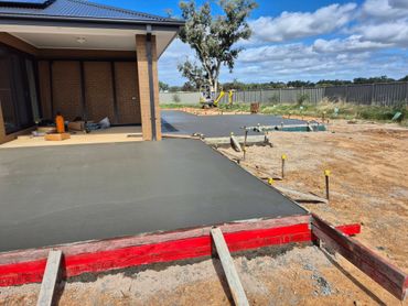 Freshly poured concrete slab near a house under construction.