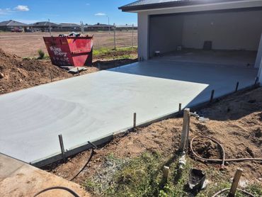 Freshly poured concrete driveway leading to an empty garage on a sunny day.