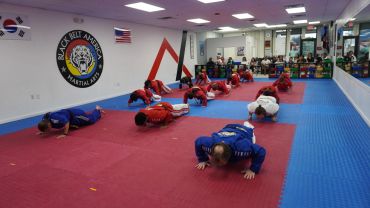 Martial arts students practicing push-ups in a training gym.