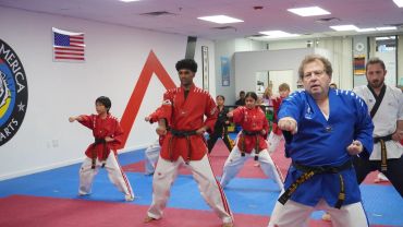 Martial arts class with diverse students practicing punches in a dojo.
