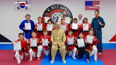 Martial arts students and instructors holding certificates in a dojo.