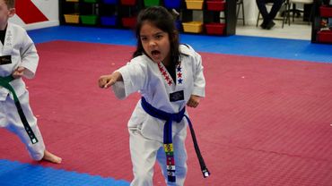 Young girl in a martial arts uniform performing a punch.
