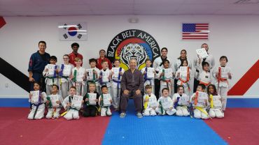 Martial arts class group photo with students and instructors holding certificates.
