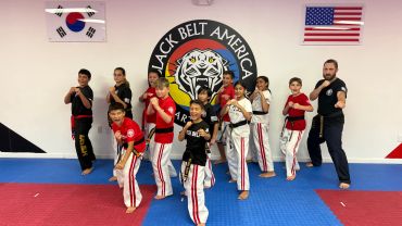 Martial arts class posing for a photo with flags.