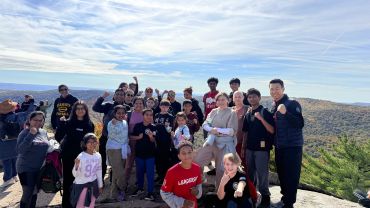 Group of people posing outdoors on a mountain with their fists up.