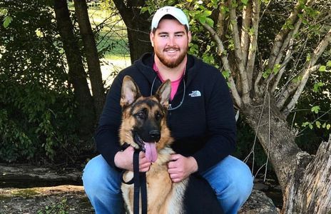 A person with a dog sitting in a field. 