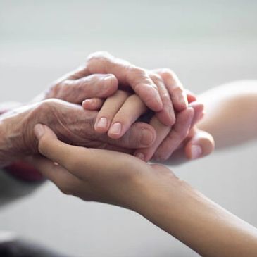 Young and elderly hands tenderly holding each other.