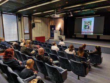 Audience listening to a speaker in a small auditorium.