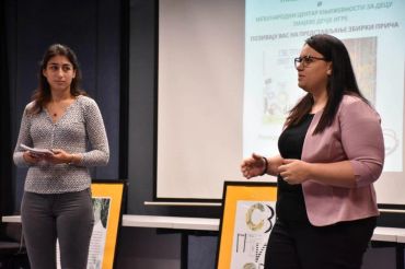 Two women speaking in front of a presentation screen.