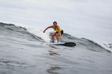 Woman surfing on a wave with determination.