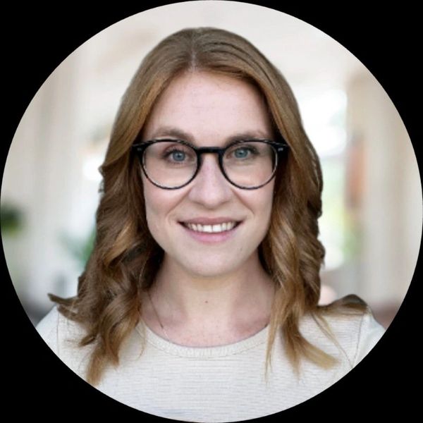 Smiling woman with glasses and curly hair.