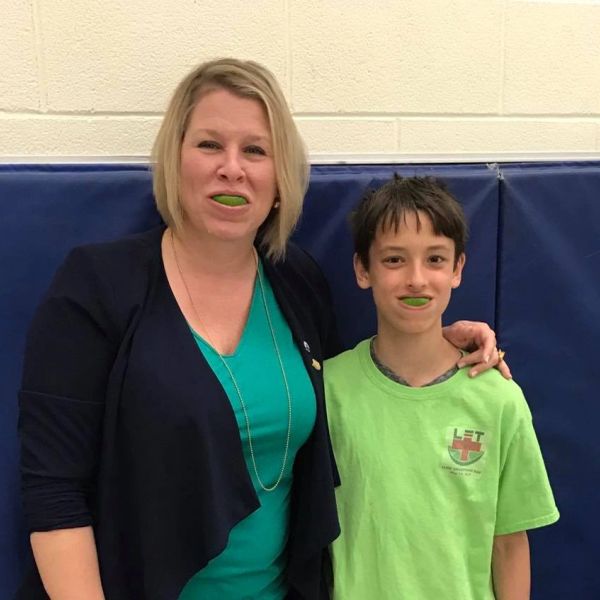 Woman and boy with green mouthguards smiling.