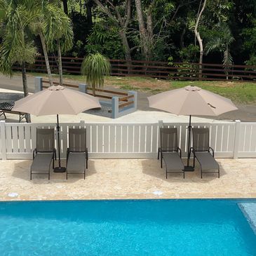 Swimming pool with tanning ledge, chaise loungers and umbrellas