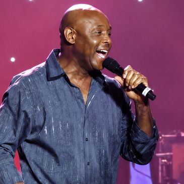 Man singing on stage with microphone.