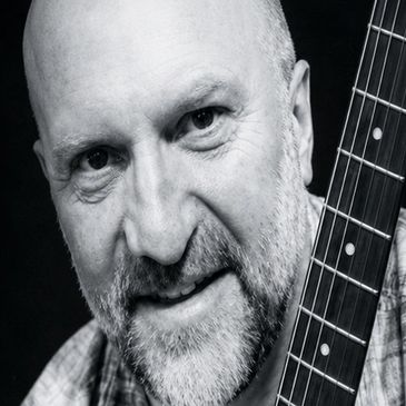 Man holding a guitar, close-up portrait.
