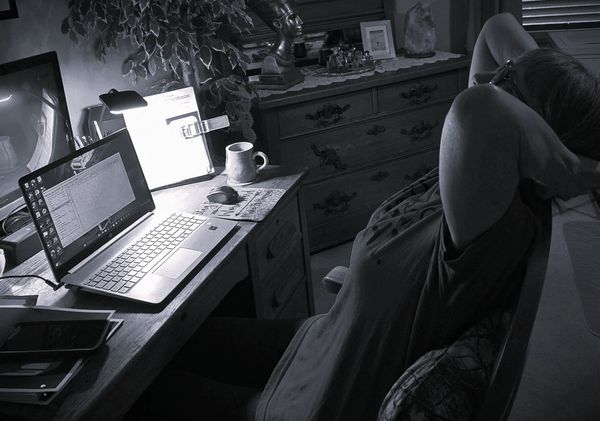 Person relaxing in a dimly lit home office.