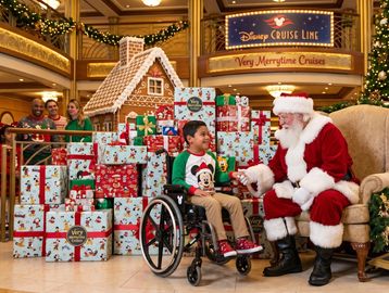 Child in wheelchair meets Santa at Disney Cruise Line holiday event.