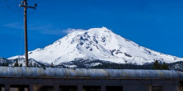 Snow-covered mountain under clear blue sky.