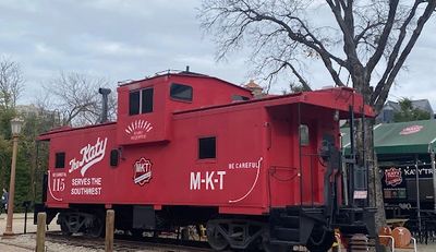 Vintage red caboose train car labeled M-K-T on display outdoors.