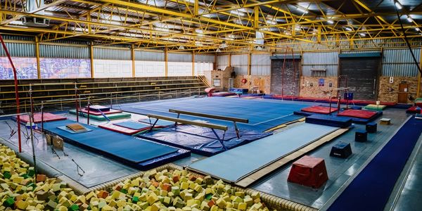Indoor gymnastics training facility with foam pit and various apparatus.