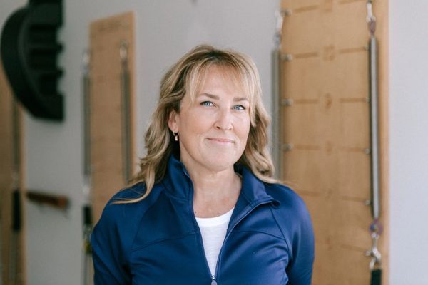 Smiling woman in blue jacket standing indoors.