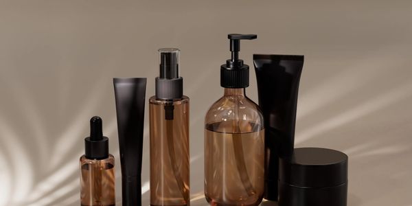 Set of modern skincare bottles and tubes in amber and black on beige background.